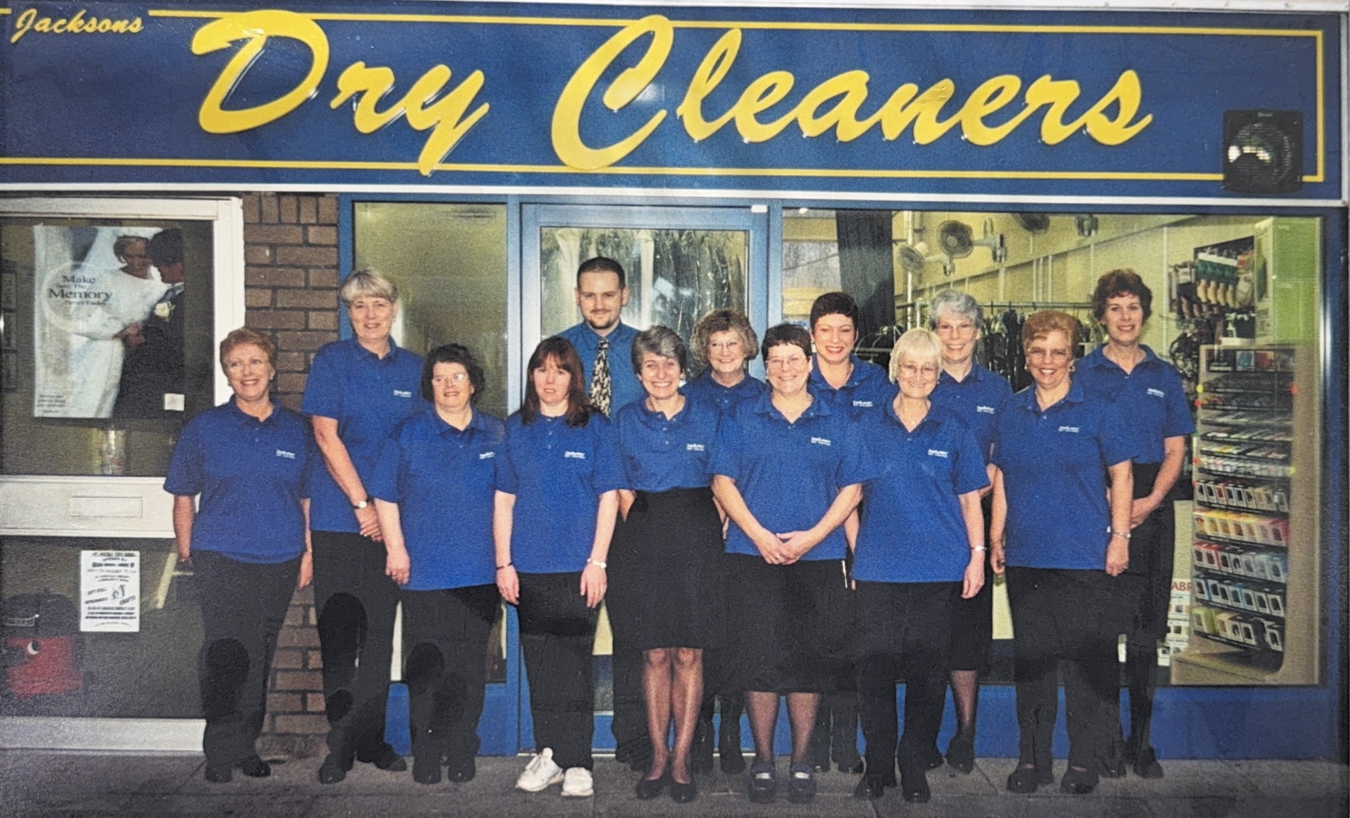 A group of people stood outside a Jacksons Dry Cleaners shop front in their uniform.