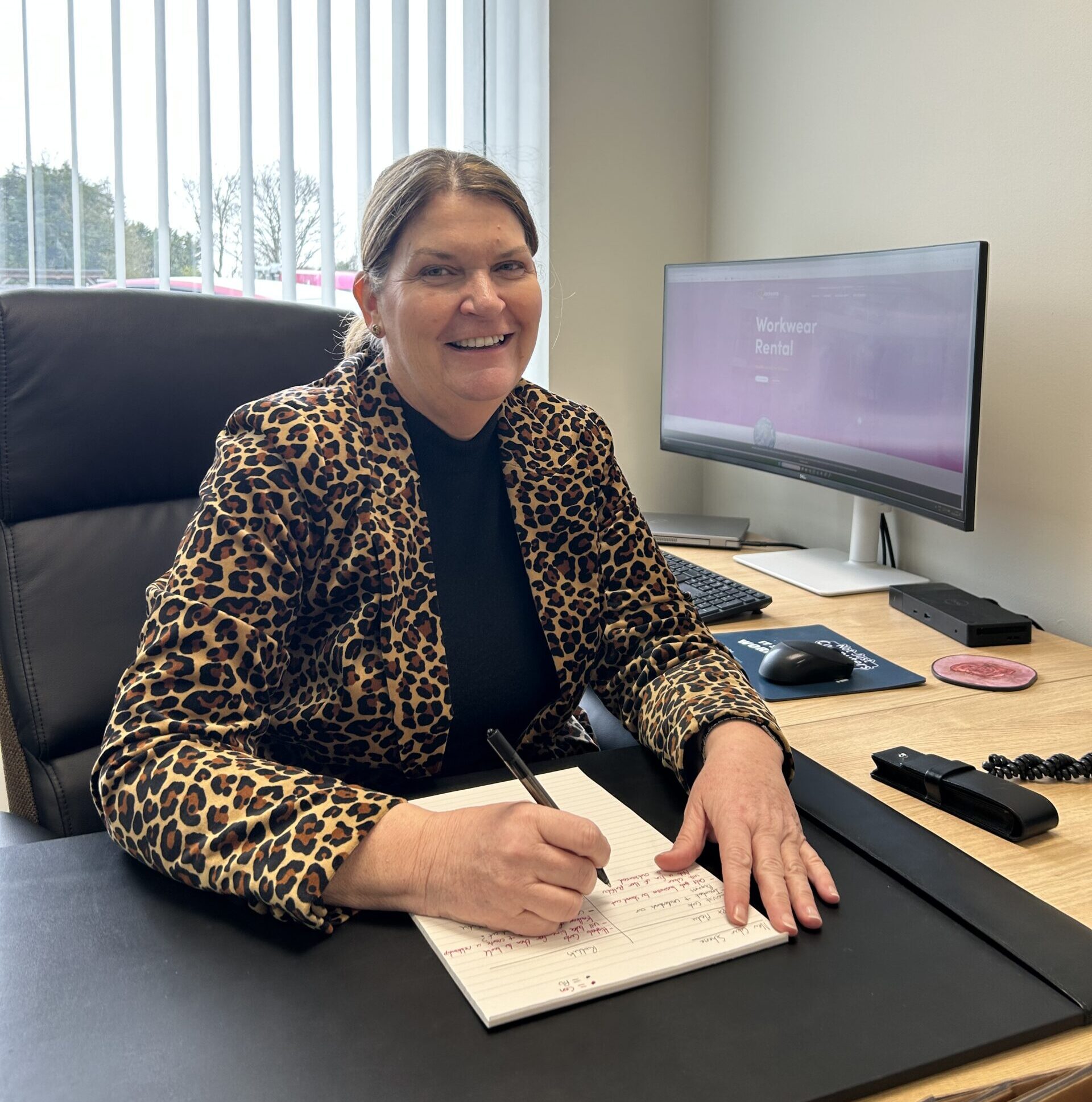 Dr Melanie Mackinder sat at a desk, looking at the camera celebrating joining Jacksons Board of Directors