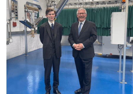 Chairman Alistair Mackinder and Compliance Director William Mackinder stood in the factory with workwear behind them.