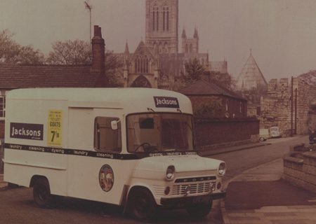 A Jacksons van parked on a street with a view of Lincoln Cathedral in the background.